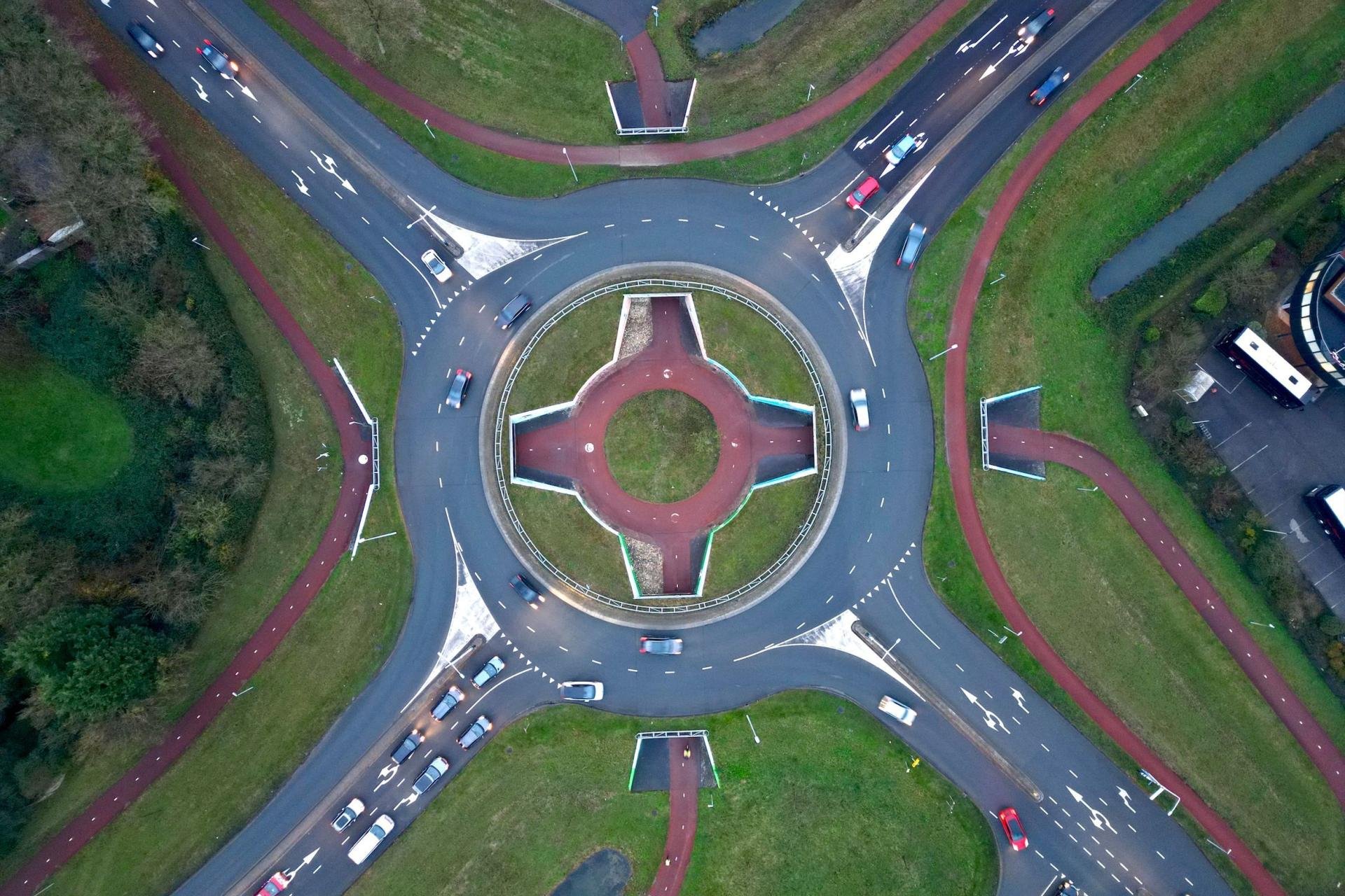 Met drone recht boven een rotonde en in de rotonde zit een fietsrotonde, duidelijk zichtbaar door het rode fietspad.