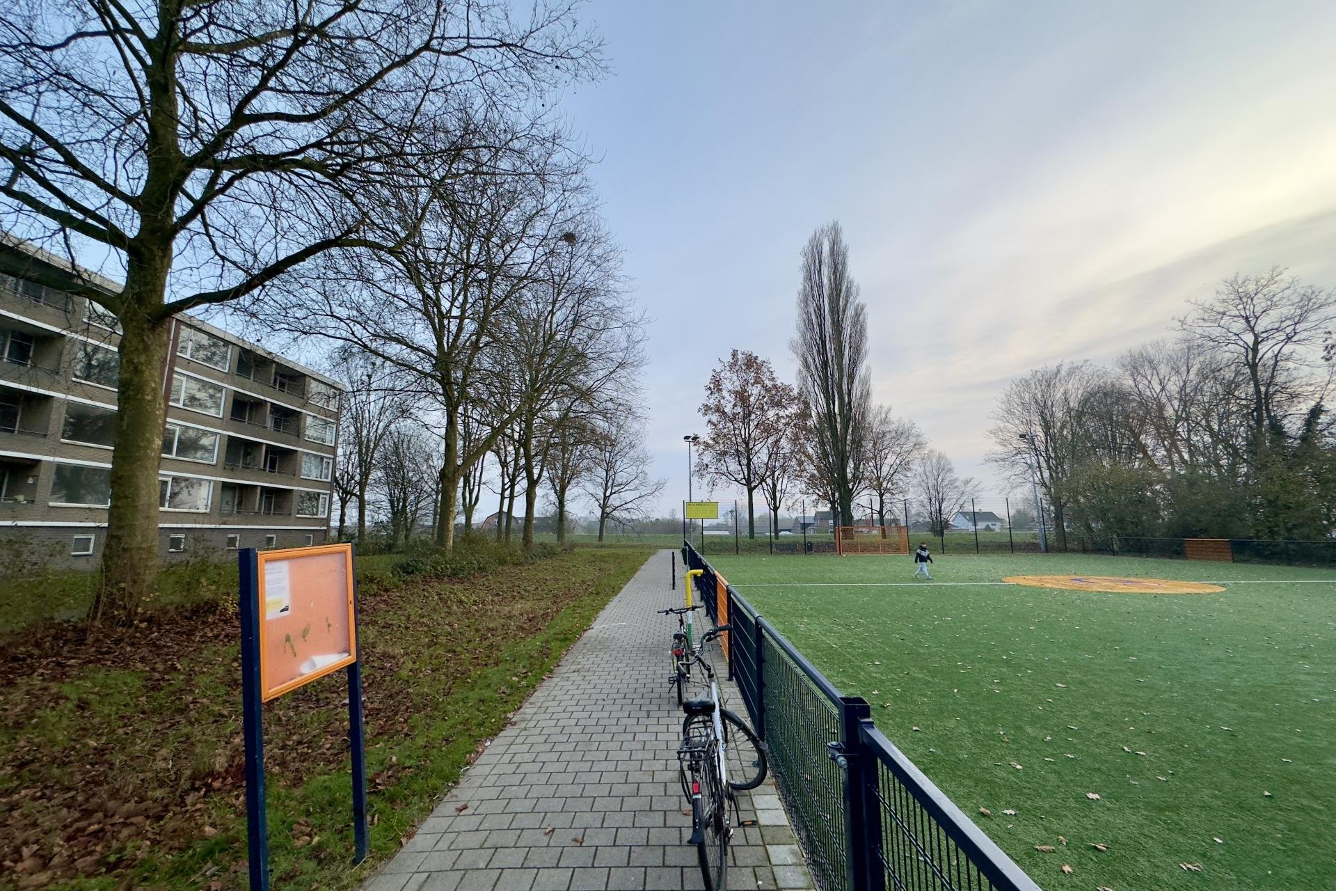 Links een flat en rechts een Cruyff Court met twee fietsen ernaast